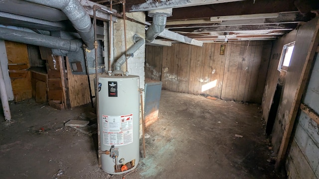 basement featuring wooden walls and gas water heater