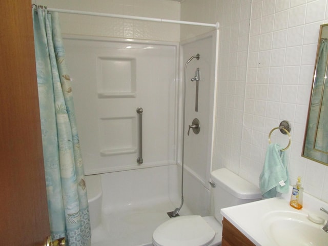 bathroom with curtained shower, vanity, tile walls, and toilet