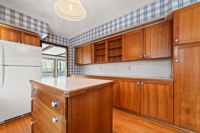 kitchen featuring light wood-type flooring, a textured ceiling, a center island, and white fridge