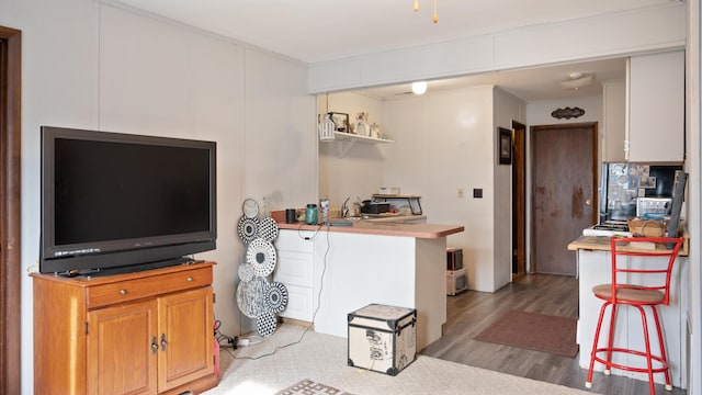 kitchen with a breakfast bar area, kitchen peninsula, and light hardwood / wood-style floors