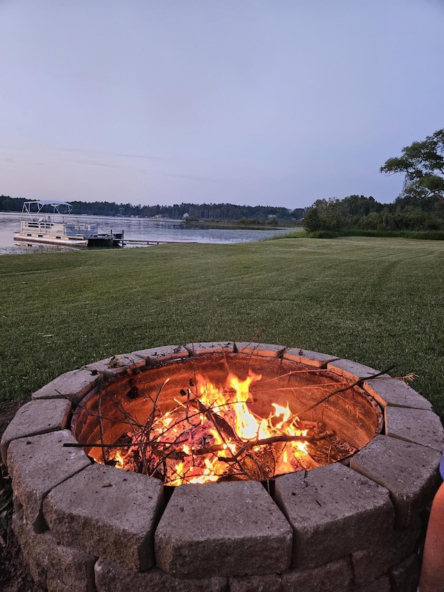 yard at dusk featuring a water view and an outdoor fire pit