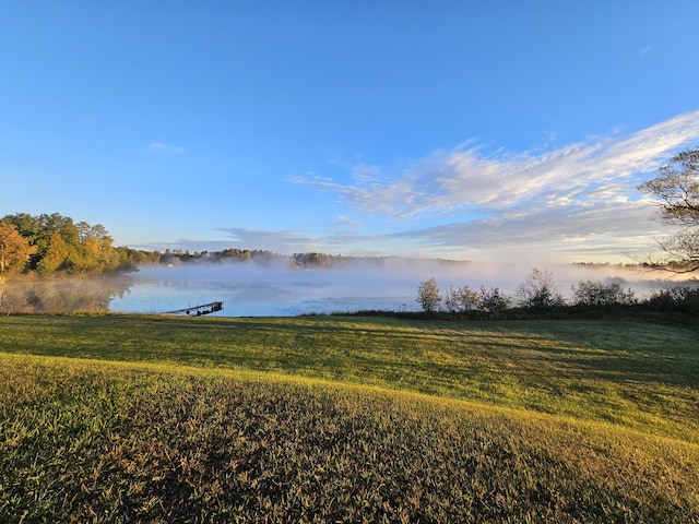 view of dock with a lawn, a water view, and a rural view