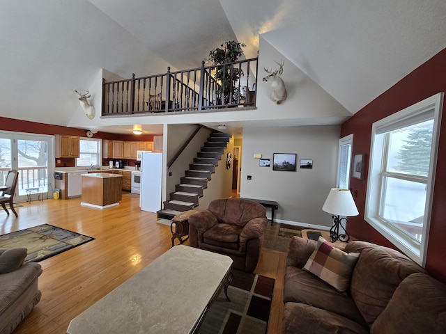 living room featuring high vaulted ceiling and light hardwood / wood-style floors