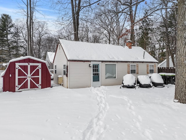 snow covered rear of property with a storage unit