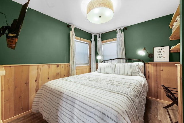 bedroom with dark hardwood / wood-style flooring and wooden walls