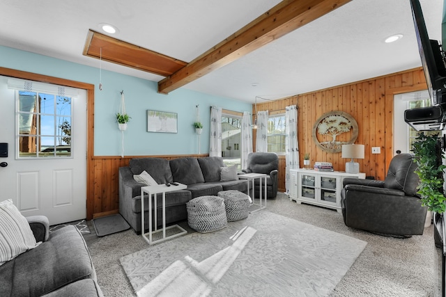 living room with carpet floors, wooden walls, and beamed ceiling