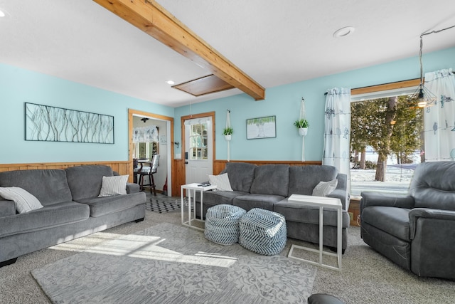 carpeted living room featuring beam ceiling and wooden walls