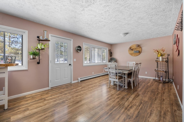 dining area featuring baseboard heating, hardwood / wood-style floors, and a textured ceiling