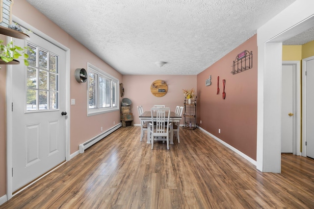 dining room with a textured ceiling, baseboard heating, and dark wood-type flooring