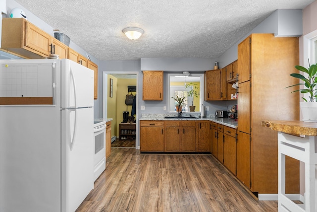 kitchen featuring stove, dark wood-type flooring, sink, a textured ceiling, and white fridge