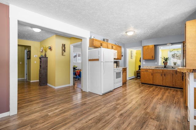 kitchen with a textured ceiling, dark wood-type flooring, and white appliances