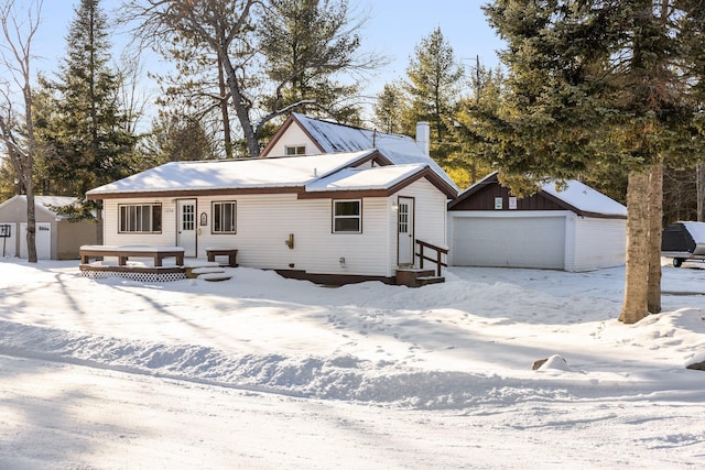 snow covered house with a shed and a garage