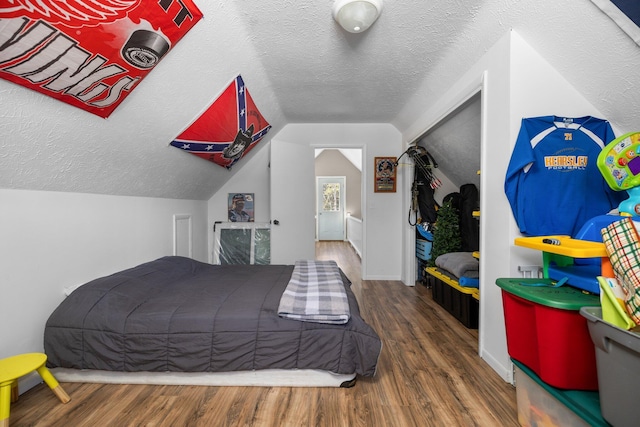 bedroom with dark hardwood / wood-style flooring, lofted ceiling, and a textured ceiling