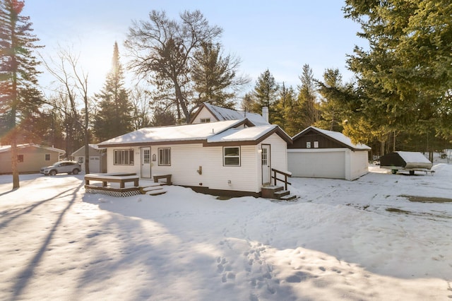 snow covered rear of property featuring an outbuilding and a garage