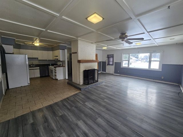 unfurnished living room with a large fireplace, ceiling fan, dark hardwood / wood-style flooring, and coffered ceiling