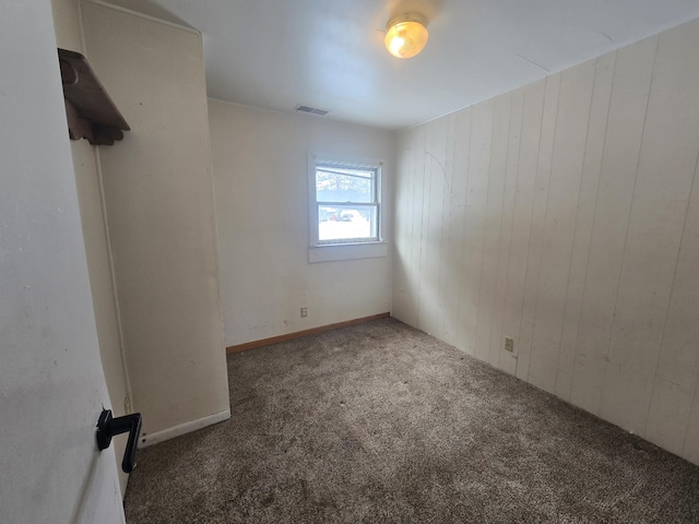 spare room with wood walls and dark colored carpet