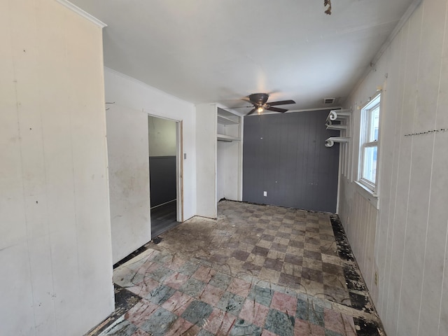 empty room with ceiling fan and wooden walls