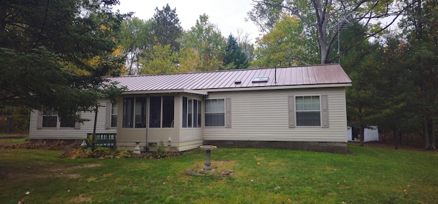 rear view of house featuring a lawn and a sunroom