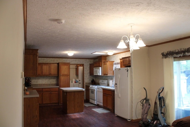 kitchen featuring white appliances, an inviting chandelier, a textured ceiling, a kitchen island, and dark hardwood / wood-style flooring