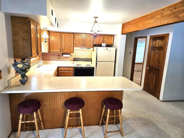 kitchen featuring white fridge, electric range oven, kitchen peninsula, a kitchen bar, and hanging light fixtures