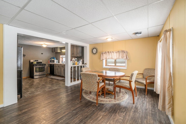 dining area with dark hardwood / wood-style flooring and a drop ceiling