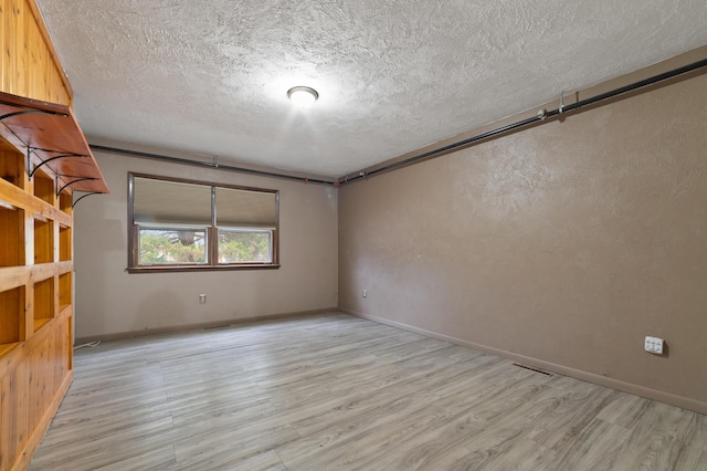 spare room featuring a textured ceiling and light wood-type flooring