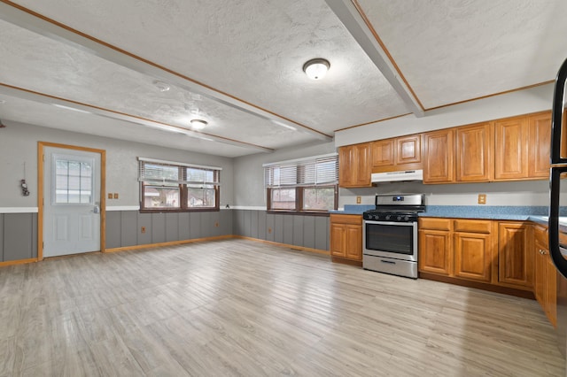 kitchen featuring stainless steel gas stove, light wood-type flooring, and a textured ceiling