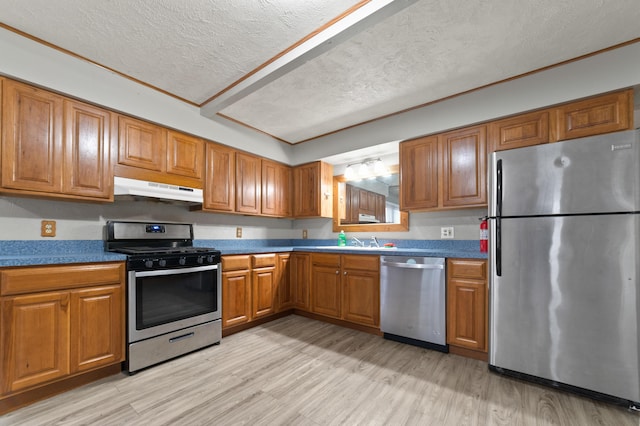 kitchen featuring a textured ceiling, sink, light wood-type flooring, and stainless steel appliances