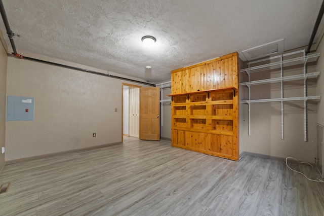 interior space featuring electric panel, a textured ceiling, and light wood-type flooring