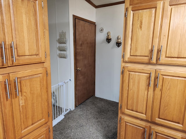 hallway featuring crown molding and dark colored carpet