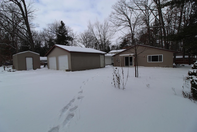 yard layered in snow with a garage and a storage shed