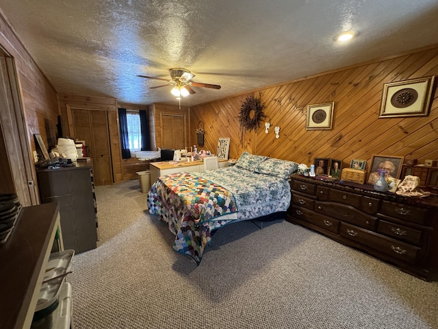 bedroom with light carpet, wooden walls, a textured ceiling, and ceiling fan