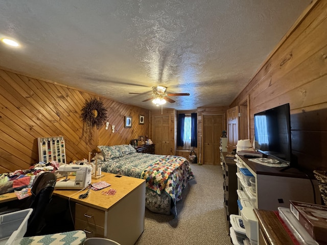 bedroom with wooden walls, light carpet, ceiling fan, and a textured ceiling