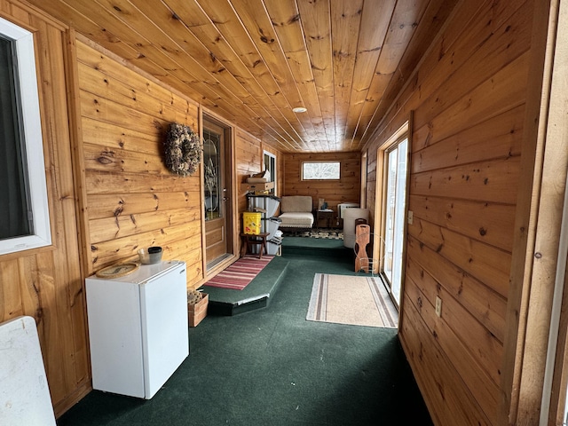 interior space featuring wood walls, dark colored carpet, and wood ceiling