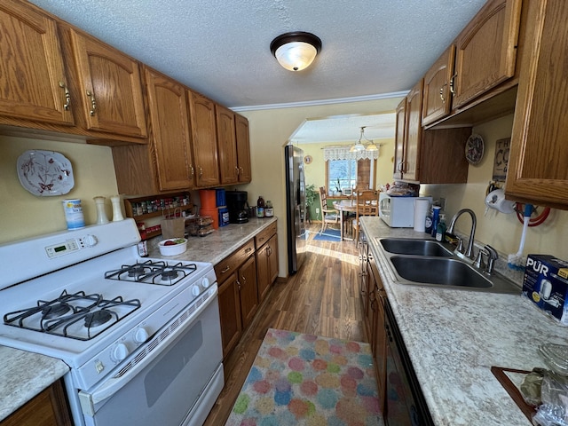 kitchen with sink, decorative light fixtures, a textured ceiling, white appliances, and dark hardwood / wood-style flooring