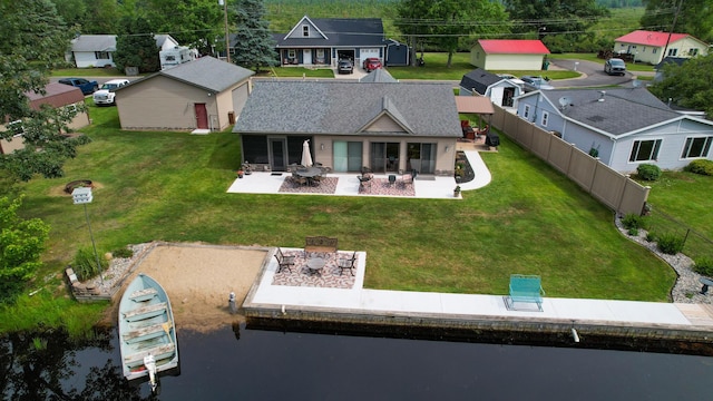 back of house with a lawn, a fire pit, a water view, and a patio