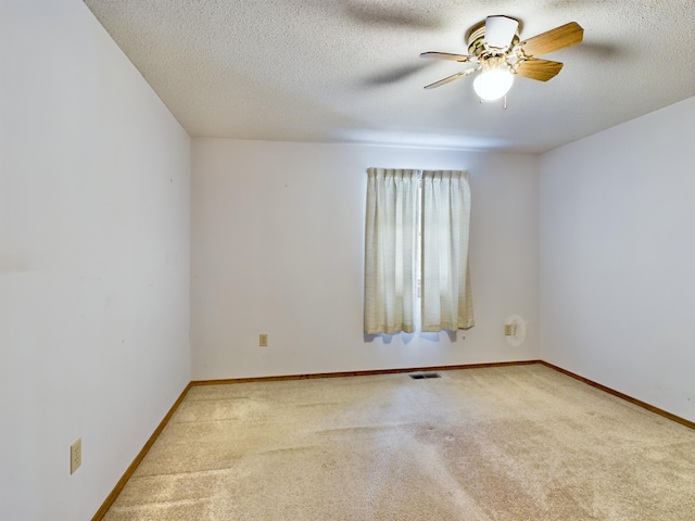 spare room with a textured ceiling, light colored carpet, and ceiling fan