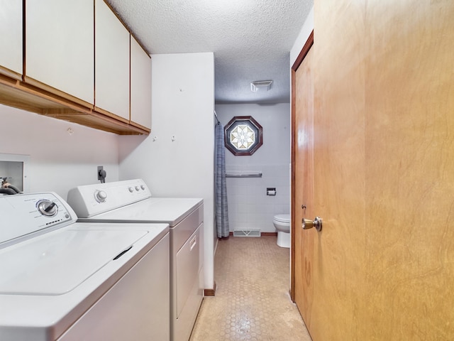 laundry room featuring separate washer and dryer, cabinets, tile walls, and a textured ceiling