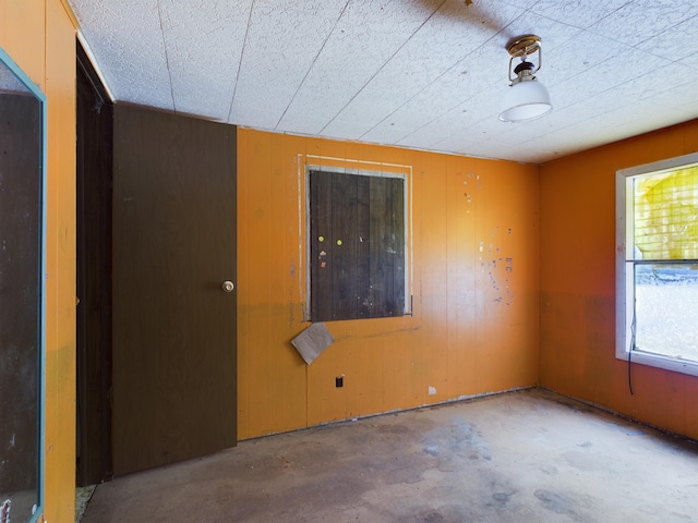 unfurnished room featuring concrete flooring and wooden walls