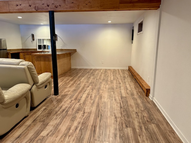 basement featuring light hardwood / wood-style flooring and stainless steel refrigerator