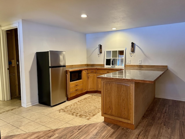 kitchen with sink, stainless steel fridge, black microwave, and kitchen peninsula