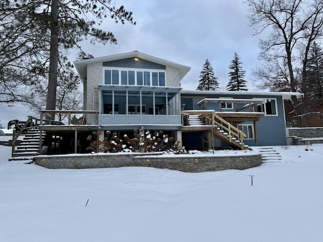 snow covered back of property with a wooden deck