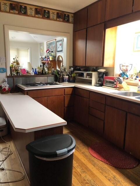 kitchen featuring gas stovetop, kitchen peninsula, light hardwood / wood-style flooring, and a breakfast bar area