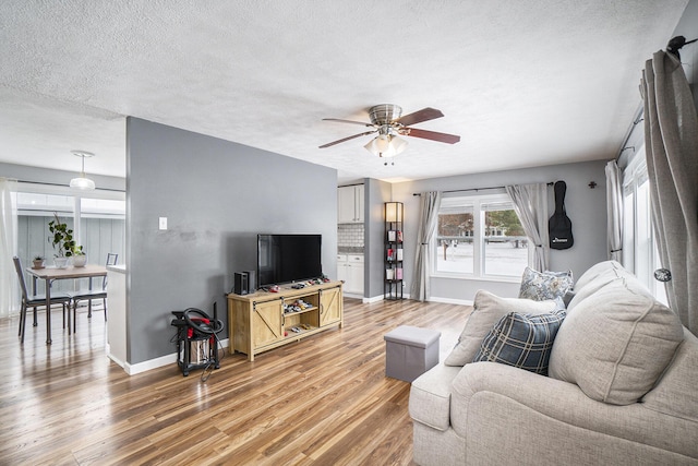 living room with ceiling fan, a textured ceiling, and wood-type flooring