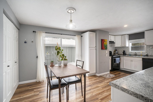 kitchen featuring black appliances, tasteful backsplash, hanging light fixtures, white cabinets, and sink