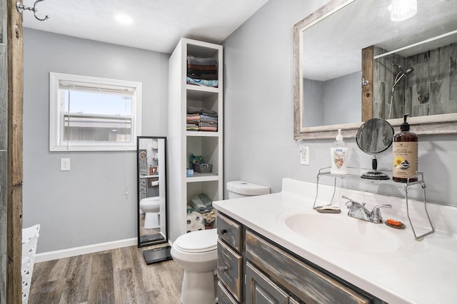 bathroom featuring a tile shower, hardwood / wood-style floors, toilet, and vanity