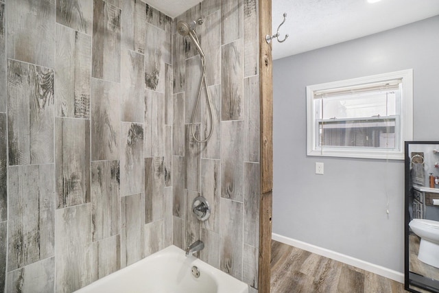 bathroom featuring hardwood / wood-style flooring, toilet, and tiled shower / bath