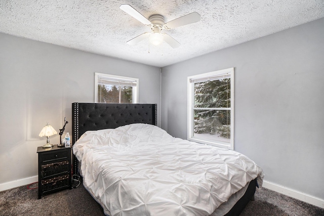 bedroom with dark colored carpet, a textured ceiling, and ceiling fan