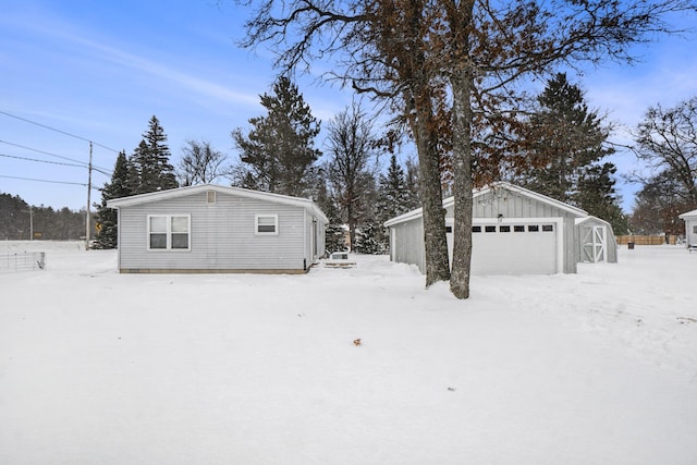 view of snow covered exterior featuring a garage and an outbuilding