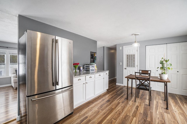 kitchen featuring light stone countertops, hanging light fixtures, stainless steel refrigerator, white cabinets, and dark hardwood / wood-style floors